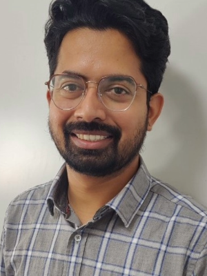 Prashanth Krishna smiling wearing glasses and a shirt, exuding a friendly and approachable demeanour.