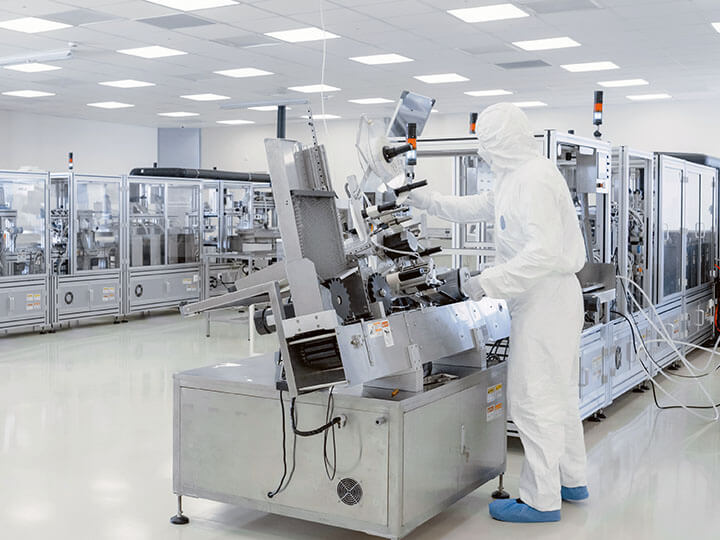 Sterile Manufacturing Laboratory with Scientists in white protective suits using machinery, computers and microscopes for research