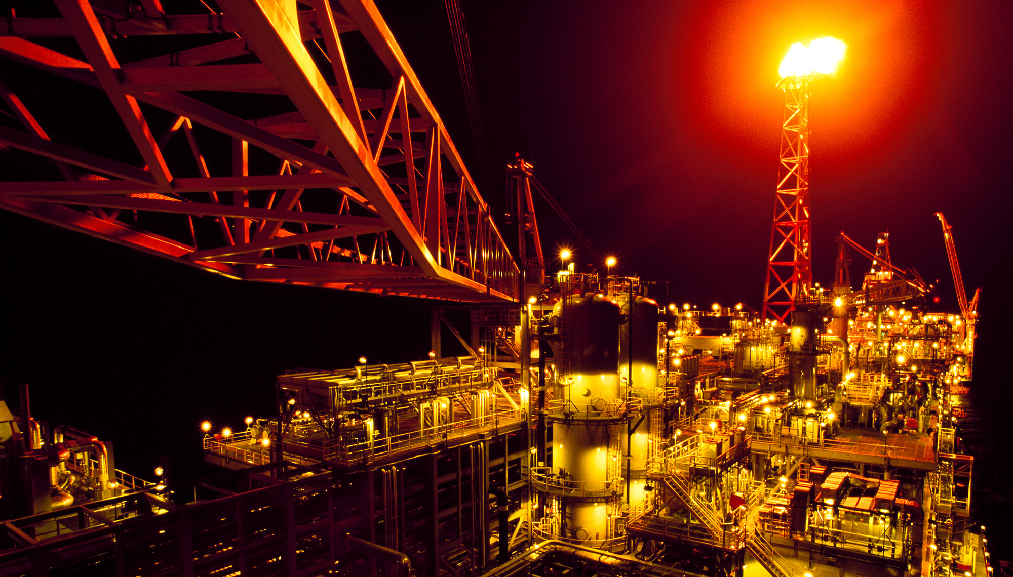 image of oil rig at night, lit by flare