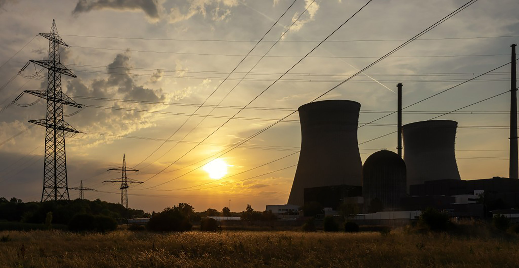 A nuclear power plant featuring cooling towers and power lines against a clear sky.