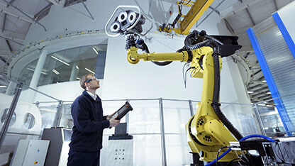 Engineer with robot in robotics research facility, low angle view