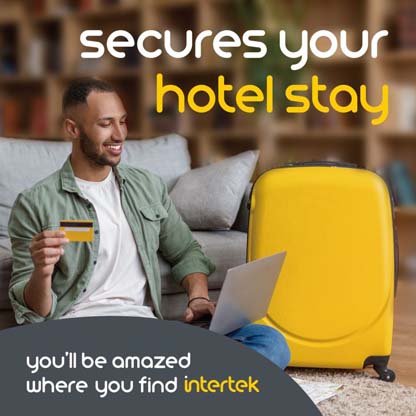 A man holding a credit card while on his laptop next to his luggage 